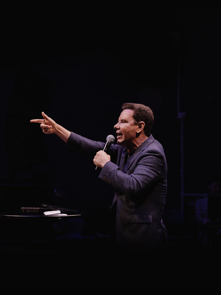 Echelon Academy MindWorks PRO Corporate Speaker - Echelon Academy UK Charismatic speaker passionately addressing audience with a microphone on stage.